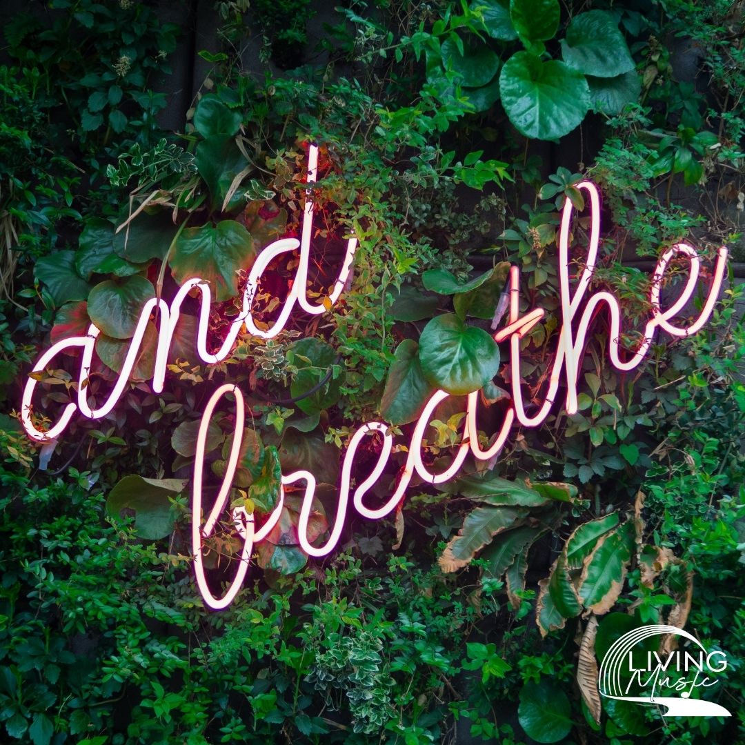 A light pink neon sign with the words "and breathe" in cursive.