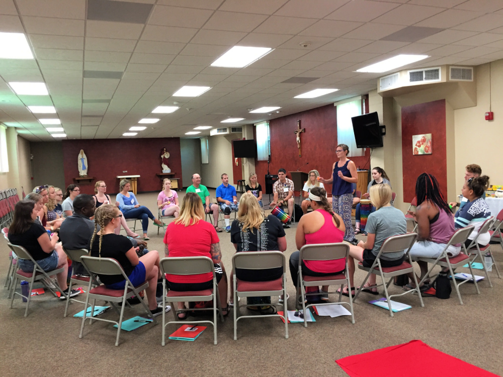 Brittany Scheer, music therapist, leading a group of teenagers and adults in a drumming workshop.